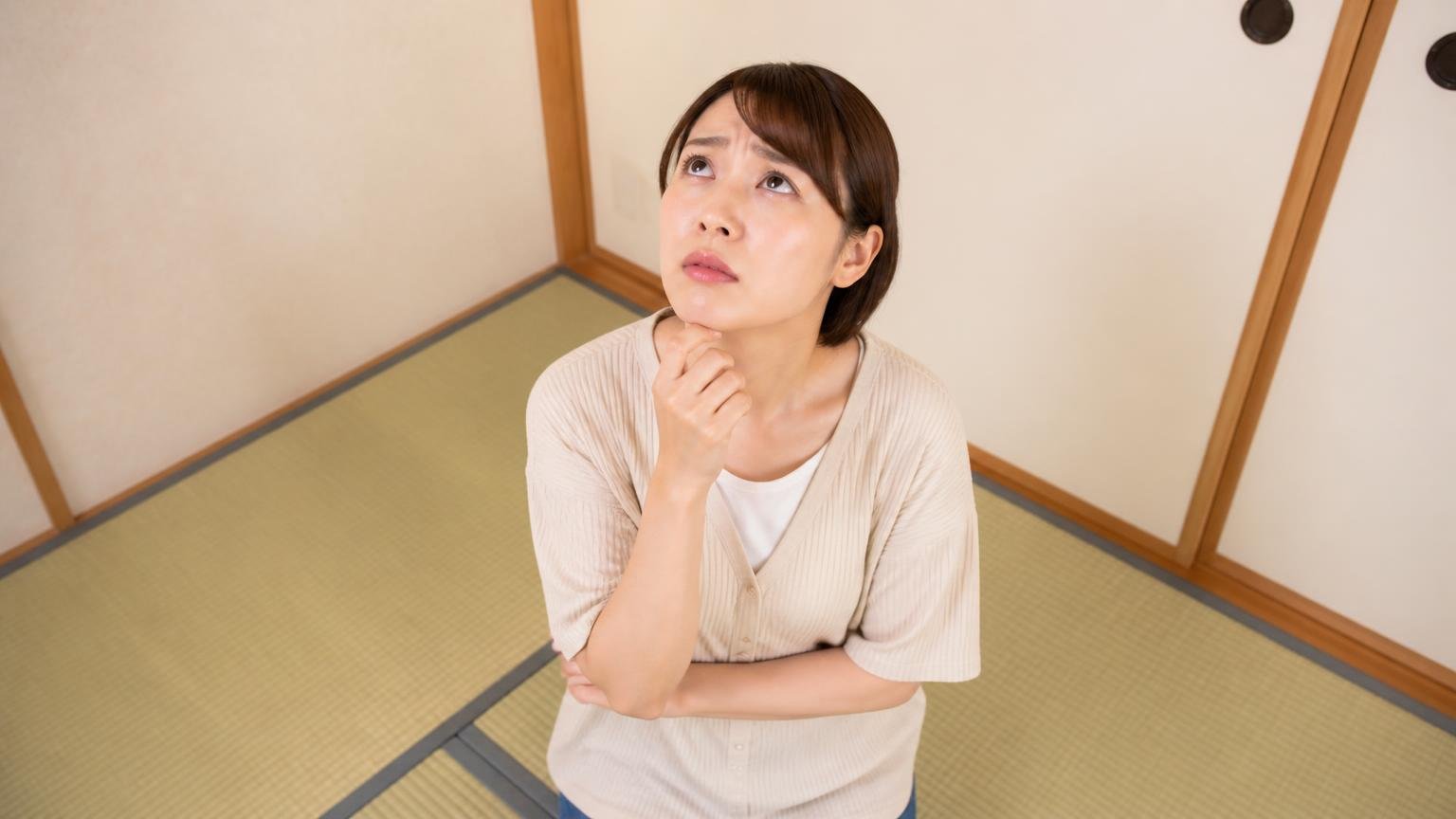 駆除後も再発の不安が残る場面 和室の畳の上で天井を見上げる女性1人 心配そうな表情