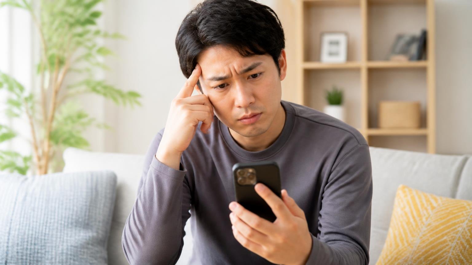 通販4サイトの平均評価は3.4〜4.27|リビングでスマホの口コミ画面を見比べる男性1人が眉をひそめる