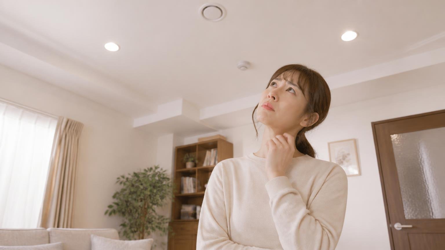 候補③生きものではない家の音。リビングの天井を見上げる女性1人が首をかしげる表情