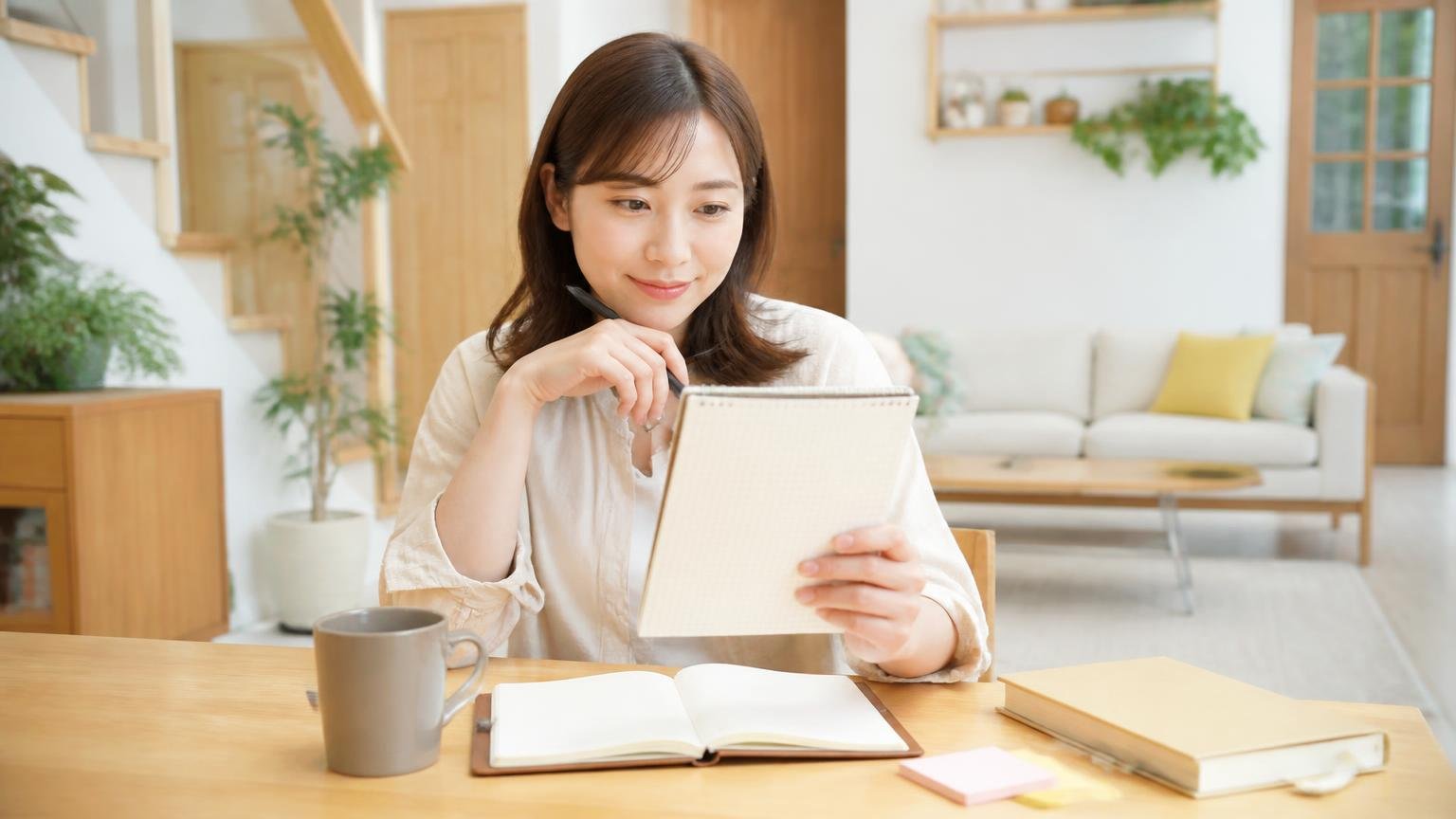 今日からやること3ステップ。木造戸建てのリビングでメモを見ながら予定を立てる30代女性1人が前向きな表情
