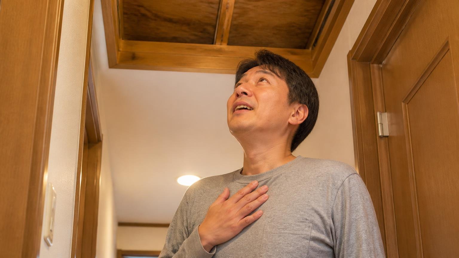 屋根裏の物音が止まった声。木造戸建ての天井裏を見上げる廊下で男性1人が安堵の表情を浮かべている