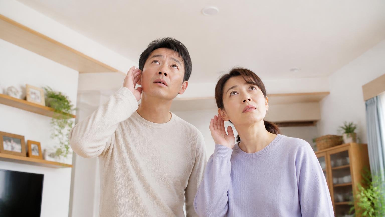 音の種類で正体を絞る|リビングの天井を見上げる夫婦2人が耳をすませ、真剣な表情