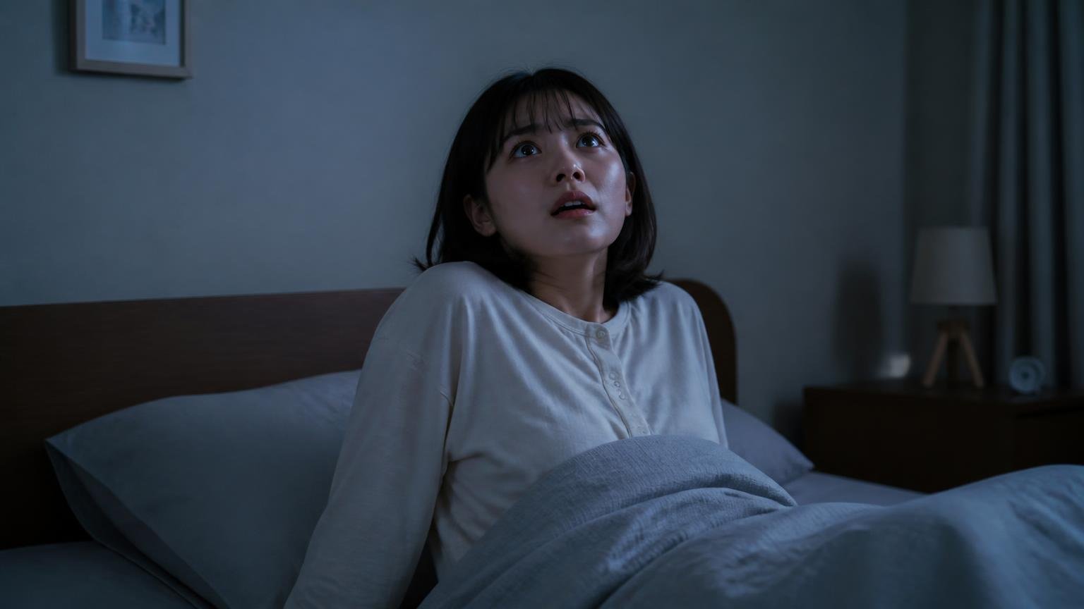 静かになった後にまた物音|深夜の寝室でベッドから身を起こし天井を見上げる女性1人が困惑した表情で固まる