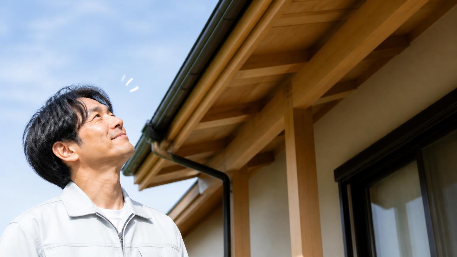向いている人の3条件 木造戸建ての屋根の軒下を見上げる住人1名 安心した表情でうなずく