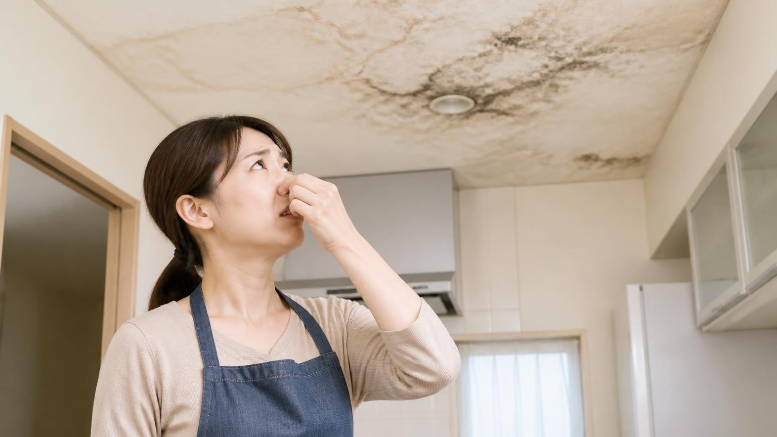 進行するとどうなるか経験した人の言葉 戸建ての台所 女性1人が天井を見上げて鼻をおさえる