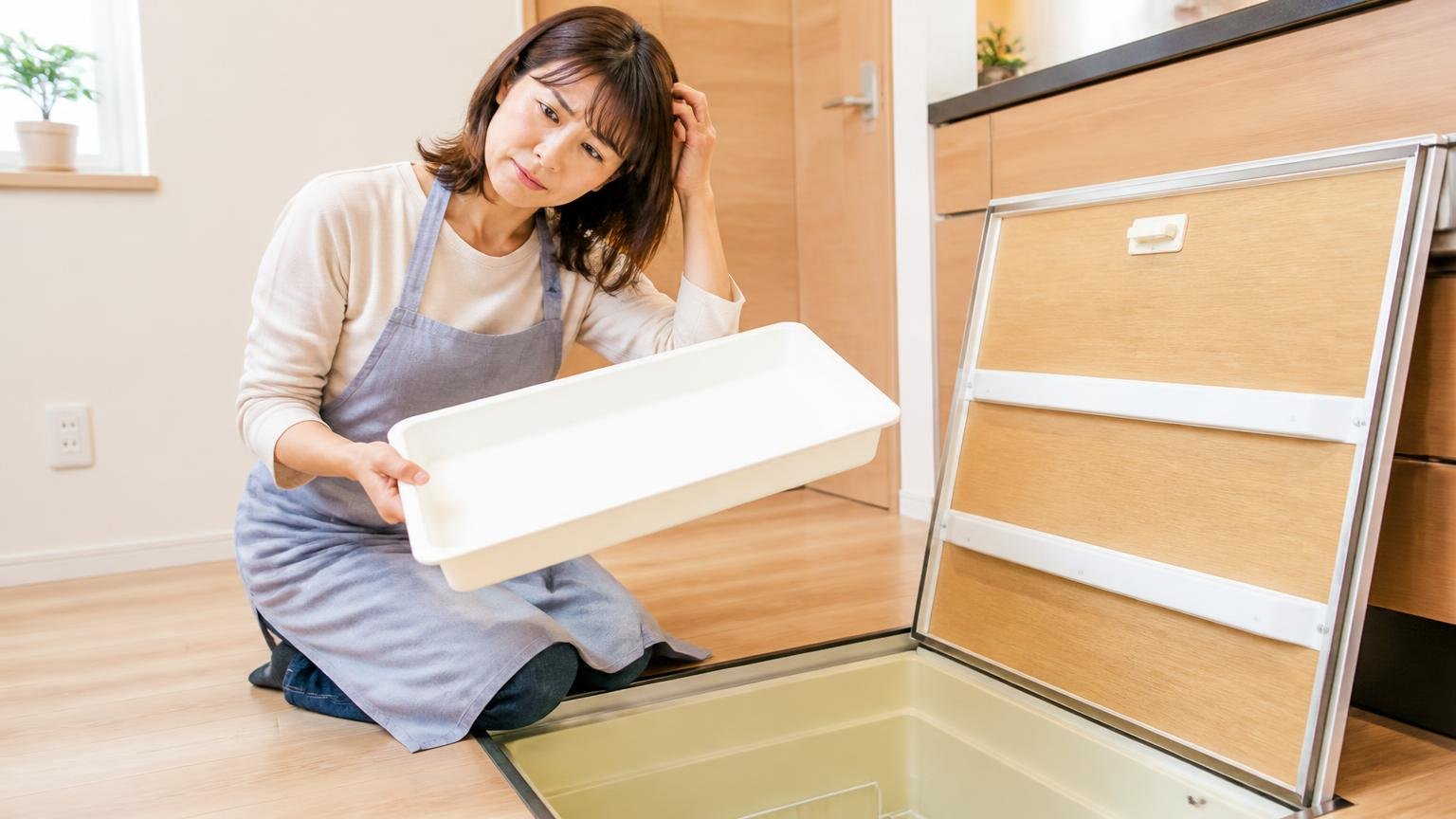 なくなったは食べたではない。住宅の床下収納の前で女性1人が空になったトレーを持ち、首をかしげて不思議そうな表情