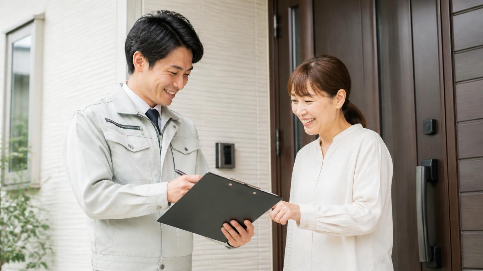 無料の現地調査から始めれば損はしない。玄関前で作業員1人と住人1人が笑顔で調査の予定を確認し合う