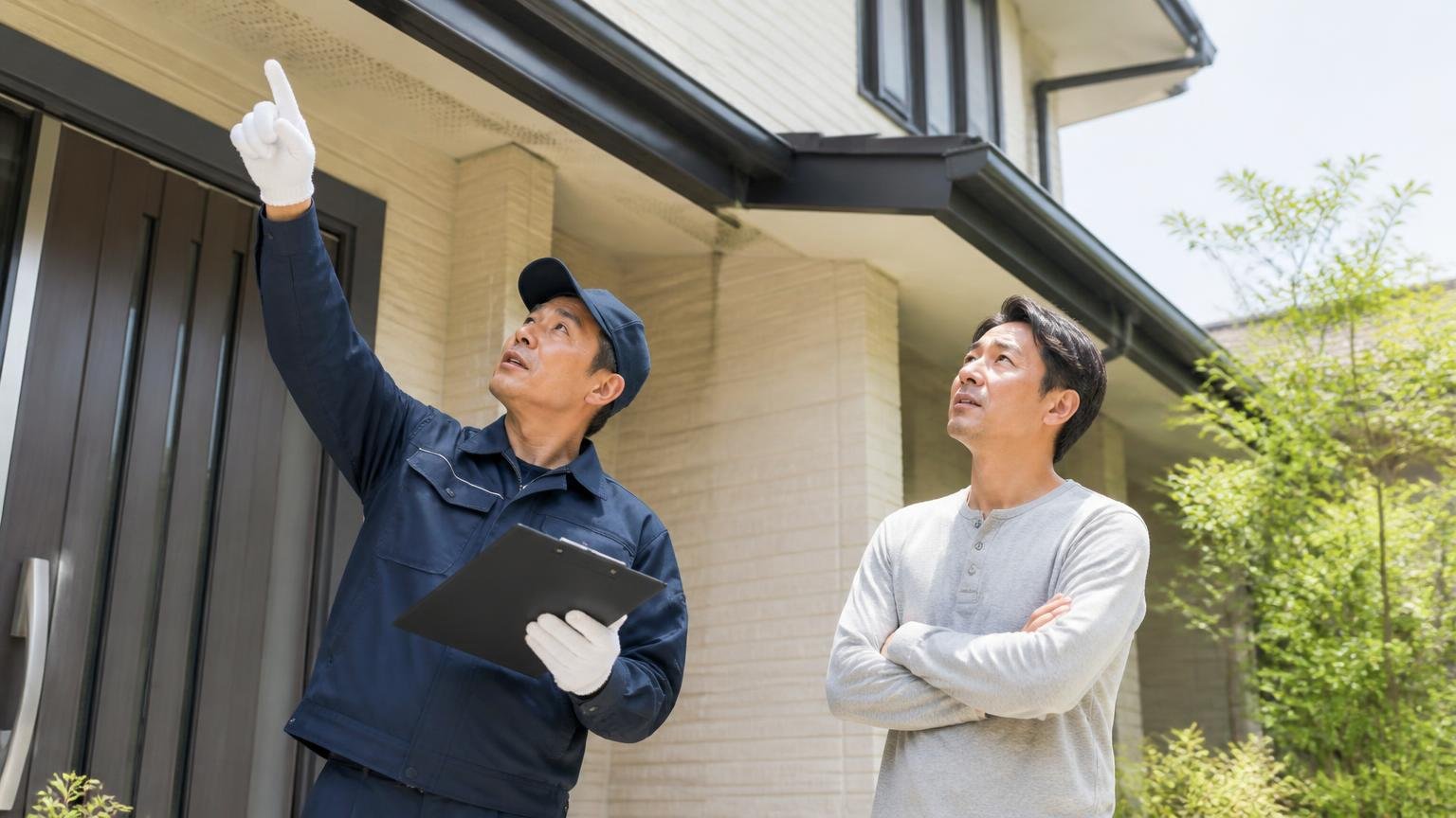 調査と見積もりが無料の害獣駆除業者 住宅の玄関前で無料調査 作業員1人と住人1人 屋根の軒下を一緒に見上げる